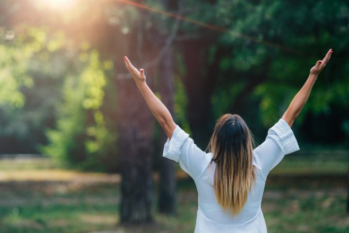 femme pratiquant méditation dynamique, dansant, les mains au ciel dans la nature