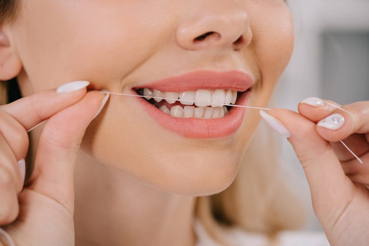 femme passant le fil dentaire sur ses dents saines